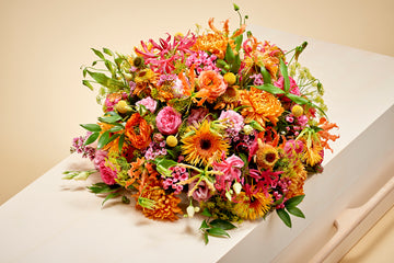 Biedermeier in warme kleuren. Oranje en roze bloemen vormen een bijzonder grafstuk.