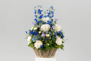 Bloemenmand Kalmte voor een crematie of begrafenis. Rouwstuk met witte en blauwe bloemen.